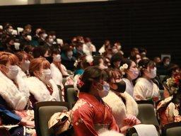 1回目の成人式の会場内の小中学校時代の恩師からビデオレターの映像を見る数人の成人男女の様子の写真