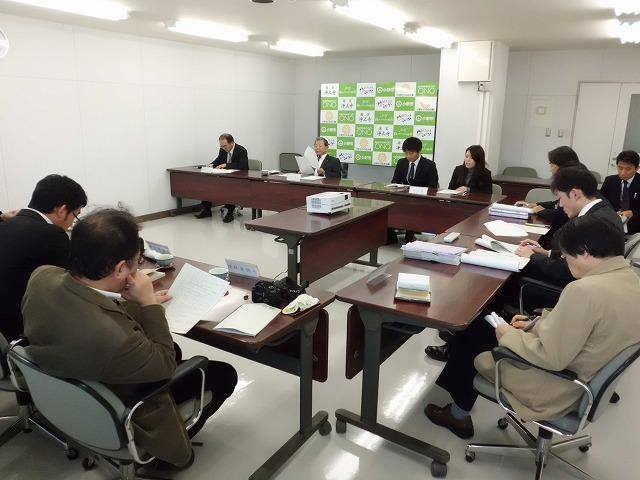 白い室内でテーブル越しに記者懇談会を行っているスーツ姿の実行委員達と大人達の写真
