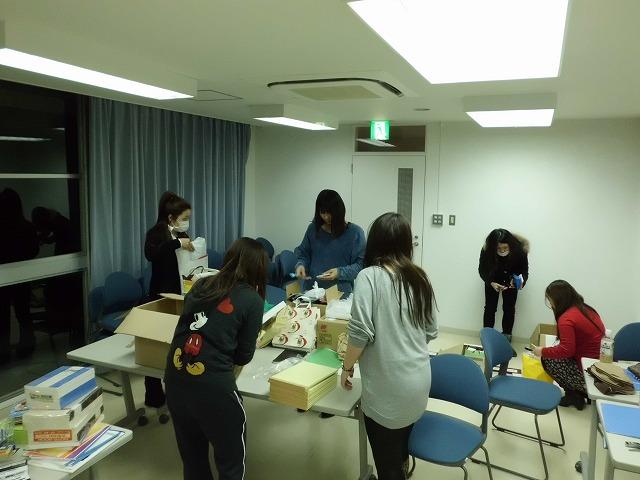 白い室内で送られてきた文具を数える実行委員の写真