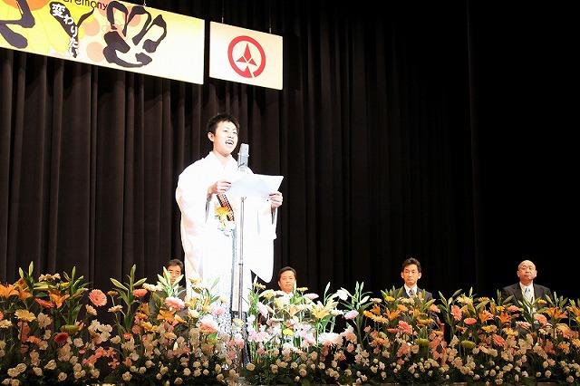 白い晴れ着姿の新成人の男性が恩師にメッセージの手紙を読み上げている写真