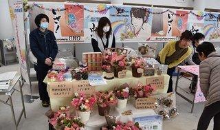 障がい者就労支援事業者とその利用者が花を商品として接客している様子の写真