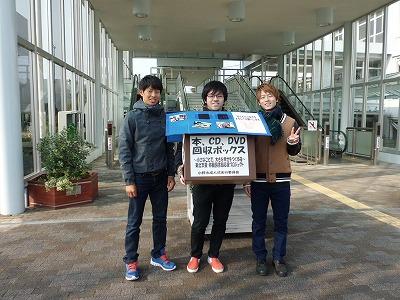 本、CD、DVD回収ボックスと書かれた箱を持っている新成人3人の写真