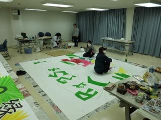 室内で大きな画用紙にイラストを書き上げる実行委員達の写真