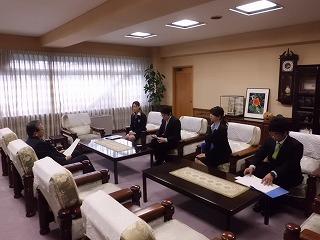 市長室で市長にテーブル越しに成人式出席の依頼を行う実行委員たちの写真