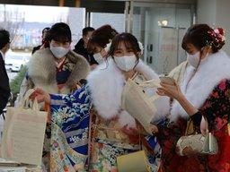 成人式の会場の玄関口に入る着物の3人の成人の女性たちの様子の写真