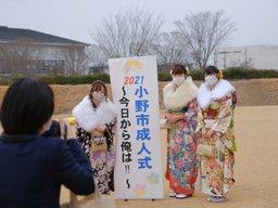 成人式の会場の外で記念写真を撮る一人の女性と写る三人の着物姿の女性の写真