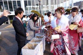 晴れ着姿の新成人達がエコバッグを貰いならぶ写真