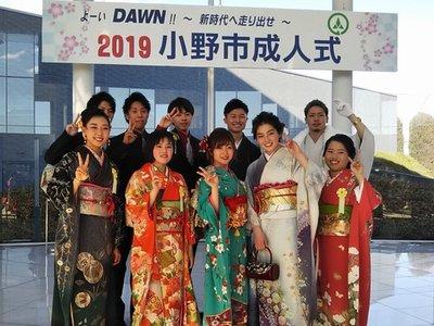 「2019 小野市成人式」と書かれたパネルを背景に記念撮影された晴れ着姿の実行委員達の写真