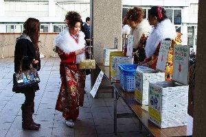 式典の入場券のペットボトルのキャップを渡す新成人とそれを回収する新成人たちの写真