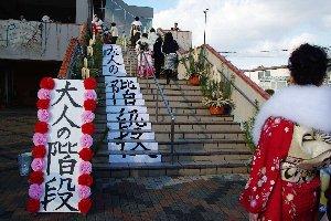 成人式のセレモニーで新成人が上る大人の階段と大人の階段と書かれた看板の写真