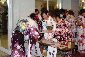 市民会館2階で受付をすます振り袖姿の新成人と受付の係を務める振り袖の新成人の写真