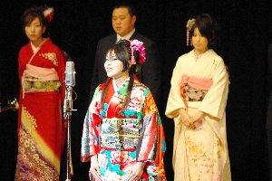 振り袖を着た女性の実行委員長が開会宣言をしている写真