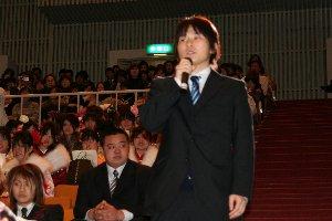 会場の座席からマイクを持って立ち上がる、スーツ姿の男性新成人の写真