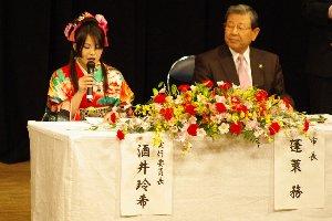 ステージ上のテーブルに着席した女性と小野市長の写真