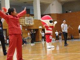 体育館内できぐるみのマスコットキャラと共にポーズを取る参加者たちの写真
