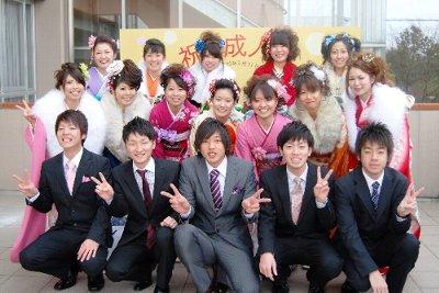 祝成人式の看板の前のスーツと振り袖姿の新成人実行委員の集合写真