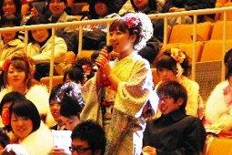 会場の中でマイクを持って立ちあがった女性と周りの新成人の写真
