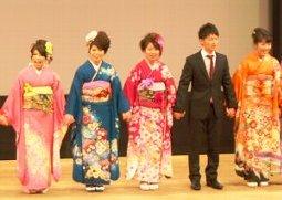 壇上に立ち手を繋ぐ新成人5人の写真