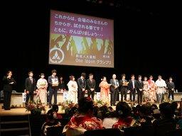 新成人3人組が4チーム並び、12人勢揃いで壇上に並んでいる写真