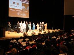 実行委員10人が壇上に上がり「栄光の架橋」を合唱している様子を眺める新成人達を後ろから撮影した写真