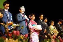 新成人と市長が並んで壇上に立ち、市長がマイクを持って式の進行をしている様子の写真