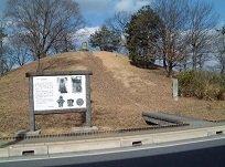 青空の下で木々が生えている王塚古墳の写真