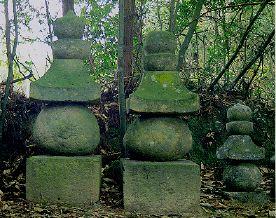擬宝珠の形をかたどった、苔むした石造五輪塔の写真