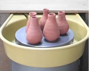 電動ろくろの上に並んだ陶芸作品の壺