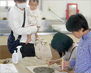 手形足形の陶板に飾り付けをするご家族