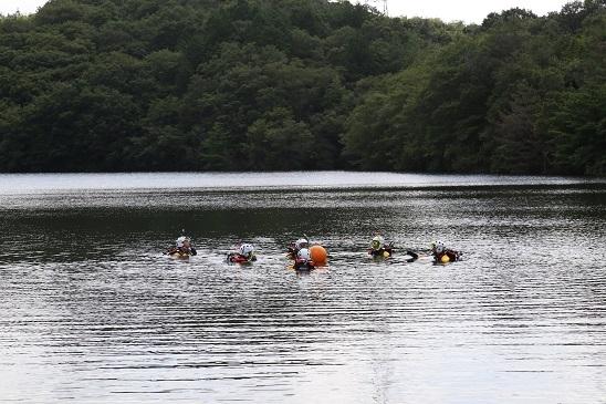 水難救助装備をしてため池に顔まで浸かり水難救助訓練をしている隊員たちの写真