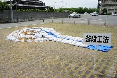 土のうが積まれたところの右手に釜段工法と書かれた立札が立てられている写真