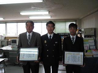 消防署の男性とその左右に並んで感謝状を手にしているスーツ姿の男性2人の記念写真