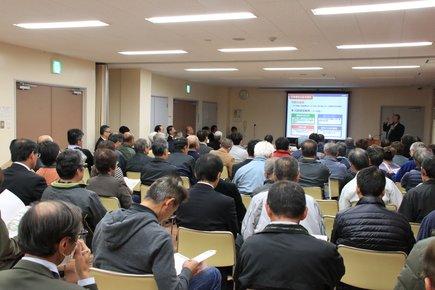 大勢の人が座ってモニターを見ている写真