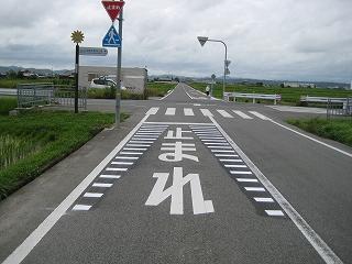 開けた視界の交差点前の道路の「止まれ」の文字が横線で囲んで強調表示されている写真