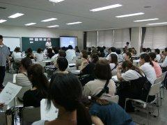 黒板の前に立ち講義を行う春川政信さんの話を椅子に座り熱心に聞く保護者たちの写真