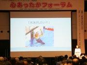 テーマが映された大きなスクリーンとその隣に立ち講演を行う伊藤真波さんの写真