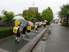 傘を差しながら並んで下校する児童たちの写真