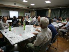 長机を合わせた複数のテーブルに6名前後の参加者が分かれて座り会話をしている写真