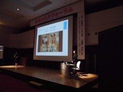 ステージに設置された大型スクリーンの脇で講義を行う水無田気流さんの写真