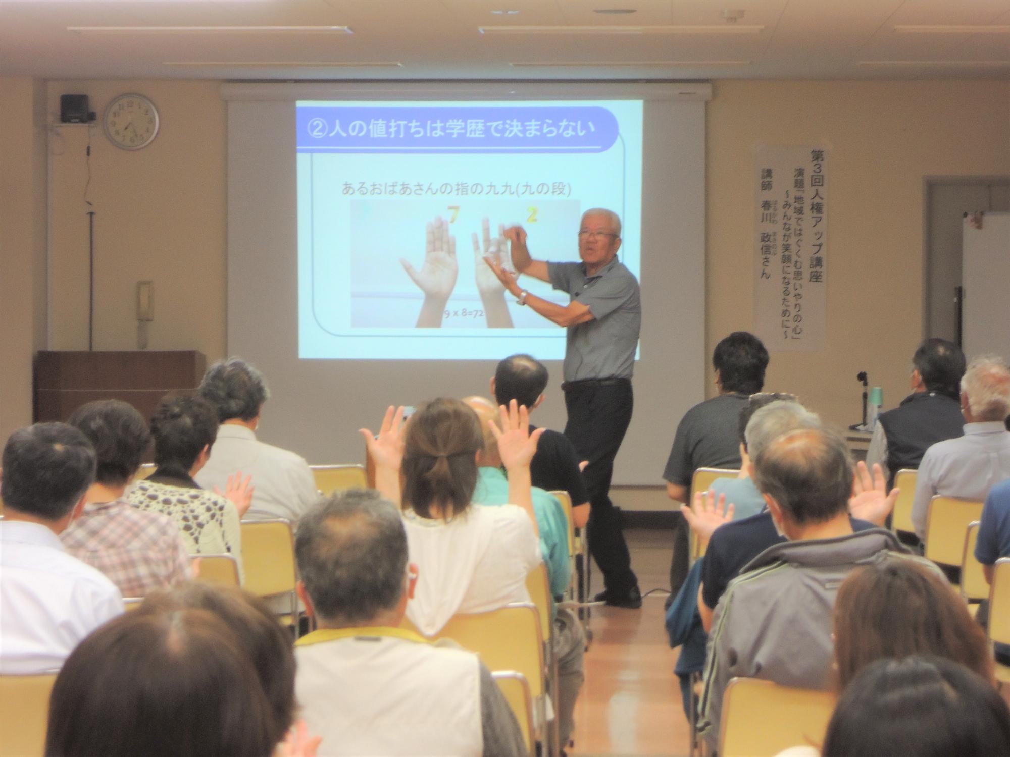手を使って講演する講師の様子