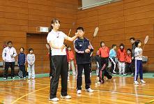小椋久美子選手が学生にバドミントンの実技指導をしている写真