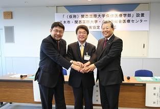 三木市と関西国際大学及び北播磨総合医療センター企業団と市長の3人で手を組んでいる写真