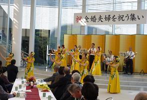 黄色い衣装を着た女性たちがステージの上でフラダンスをを踊っている写真
