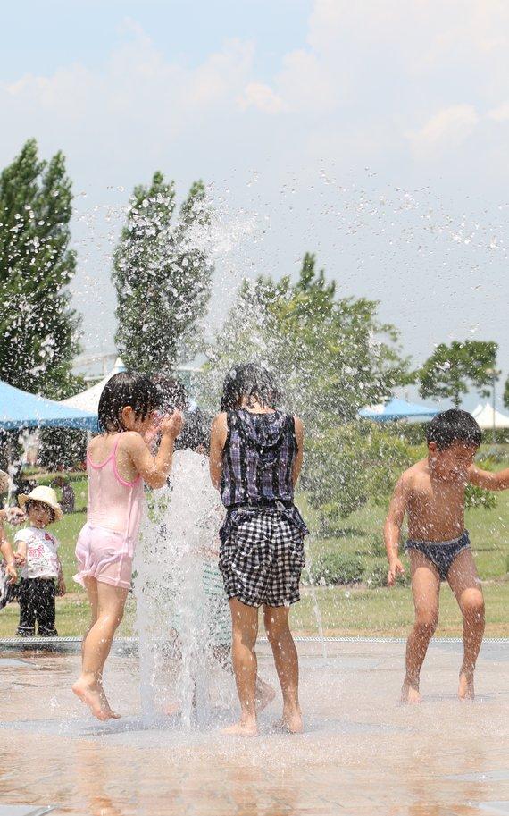 遊べる噴水で子供たちが水着で水遊びをしている様子の写真