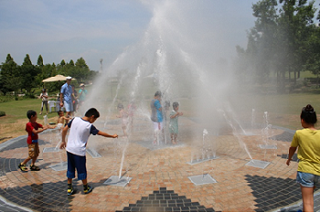 ひまわりの丘公園の親水施設で子供たちが水遊びをしている写真
