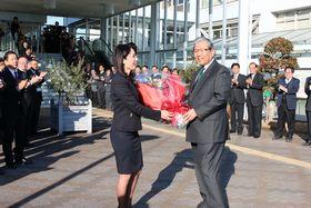 スーツを着た女性から花束を受け取っている市長の写真