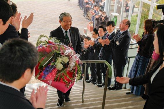 花束を抱えながら笑顔で階段を上っている市長の写真
