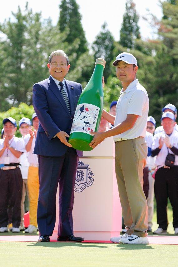 市長から時松隆光プロに「おの恋」生一本純米吟醸1年分の大きなボトルを贈呈している様子の写真