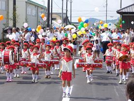 小学生たちが太鼓などを持ってパレードを行進している写真