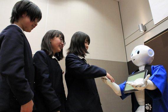 女子中学生が人型ロボット「ペッパー」と握手をしている写真